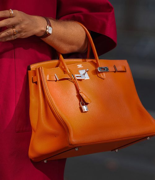 Paris, France - October, 4, 2025: Man wears Hermes orange Birkin bag. Fashion outfit handbag details, street style look accessories, luxury leather accessory
